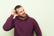 © luismolinero - Colombian man with sweatshirt over green wall having doubts and with confuse face expression