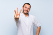 © luismolinero - Colombian man over isolated blue wall happy and counting three with fingers