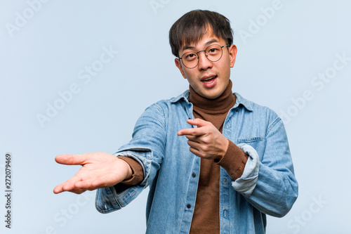 Cuadros en Lienzo Young chinese man holding something with hand