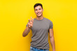 © luismolinero - Handsome man over isolated yellow wall happy and counting three with fingers