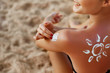 © verona_studio - Young woman with sun shape on the shoulder holding sun cream bottle on the beach