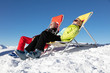 © StudioWout - Senior couple  sunbathing in a deckchair near a snowy ski slope