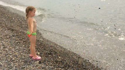 a little girl throws stones into the sea, summer vacation by the water