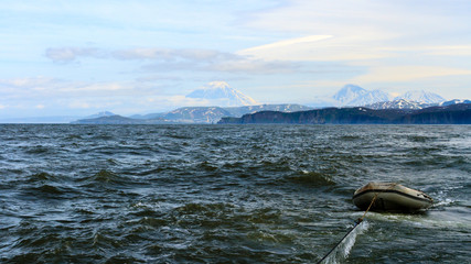 Wall Mural - Boat in the sea. Beautiful view of the volcano Vilyuchinsky from ocean, Kamchatka Peninsula, Russia