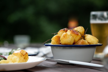 Wall Mural - Baked potatoes with herbs on a wooden table in the garden. Delicious vegetarian food outdoors, country lunch.