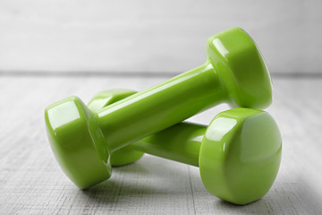 Bright dumbbells on wooden floor. Home fitness