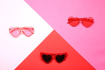 Flat lay composition with heart shaped sunglasses on color background