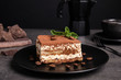 Composition with tiramisu cake on table against dark background