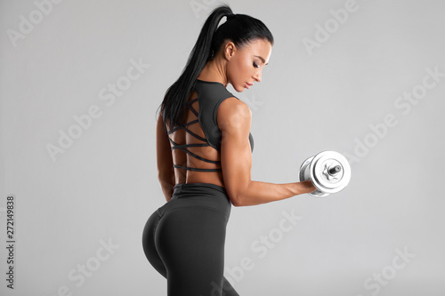 Cuadros en Lienzo Fitness woman doing exercise for biceps on gray background