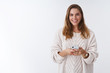 © Cookie Studio - Studio shot charming happy smiling woman holding smartphone looking camera positive grinning communicating using app featurused. Female blogger posting pic online smm working via phone