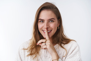 Wall Mural - Close-up devious creative charismatic joyful woman making prank fooling around smiling giggling smiling broadly have secret, shushing saying shh holding index finger pressed mouth, white background