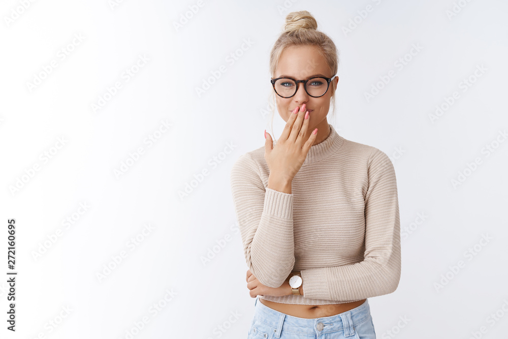 Attractive young glamour girl making fun over coworker giggling smiling holding laugh as smirking and covering mouth with palm hiding chuckle as posing over white background - obrazy, fototapety, plakaty 