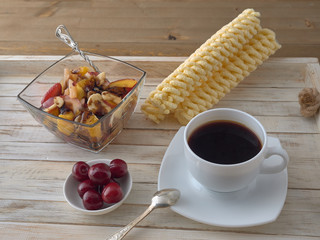 Wall Mural - Breakfast.Fruit salad.Black coffee and croissant.On a wooden tray