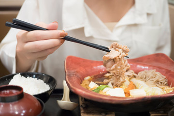 Wall Mural - happy smiling woman eating shabu or sukiyaki, Asian Japanese hot pot food concept