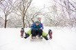 © zhukovvvlad - A woman with her son rides down the hill in a sleigh and screaming.