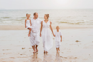 Wall Mural - Happy young family on the sunset at the beach.