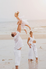 Wall Mural - Happy young family on the sunset at the beach.