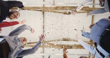 Wall Mural - Close-up happy multiethnic group of business people joining hands together, clapping under confetti at office background