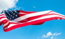 American Flag In Blue Sky Background. United States Flag