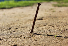 Old Rusty Nail Sticking Out Of The Ground.
