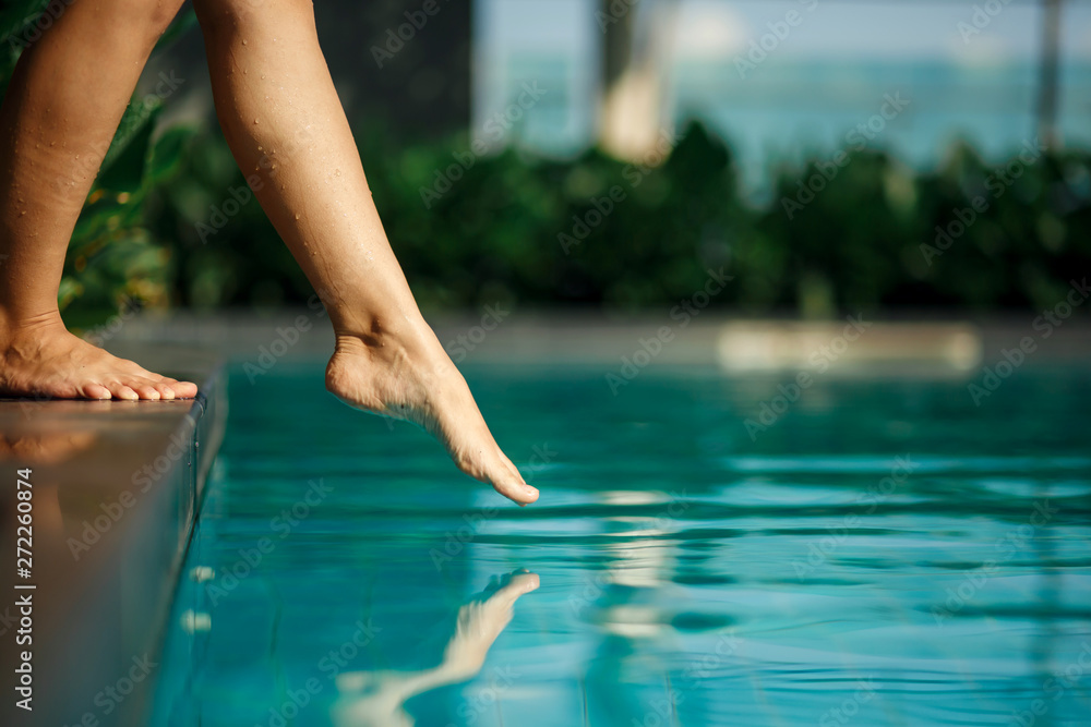 Closeup young female leg touch blue water in swimming pool - obrazy, fototapety, plakaty 
