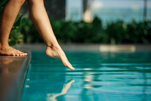 Closeup Young Female Leg Touch Blue Water In Swimming Pool