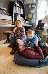 Wall Mural - Happy young family playing on the floor at rustic room