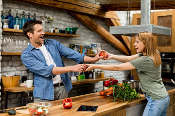 Wall Mural - Lovely cheerful young couple cooking dinner together