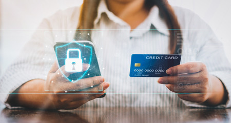 Woman holding smartphone and credit card with padlock icon on digital display cyber security internet and networking, Concepts online shopping for protection.