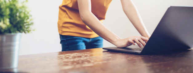 Closeup of woman's hands typing on laptop computer and searching web, browsing in the workplace at office.