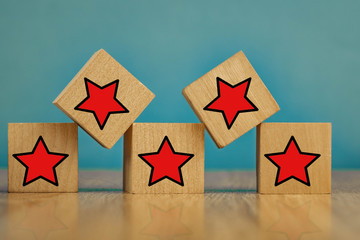 Red stars on wooden cubes on a blue background. Stars mean assessing quality. five-point rating system.