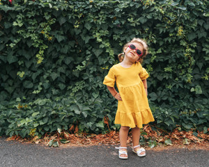 Portrait of Cute Blond Girl in Clothing Posing in  Sunny Day and Looking at the Camera at outdoors.