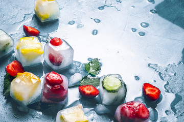 ice cubes with fruit and broken ice on a stone blue background with mint leaves and fresh fruit. min