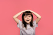© Marharyta Hanhalo - Portrait of funky cute astonished surprised child kid little girl touch hand head shout yell wonder hear incredible information bargain impressed dressed grey clothing isolated pink background