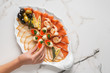 Seafood platter with salmon slice, pangasius fish, red caviar, shrimp, decorated with olives and lemon on marble background.  Mediterranean appetizers, top view