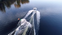 Wake boarding. Motor boat pulls a surfer riding the water surface on his board. Aerial view