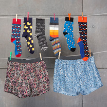 Many Men's Socks And Underpants Hang On Clotheslines, As If Being Dried, The Concept Of An Assortment, Against A Concrete Wall