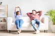 © Pixel-Shot - Happy young couple resting together on sofa at home