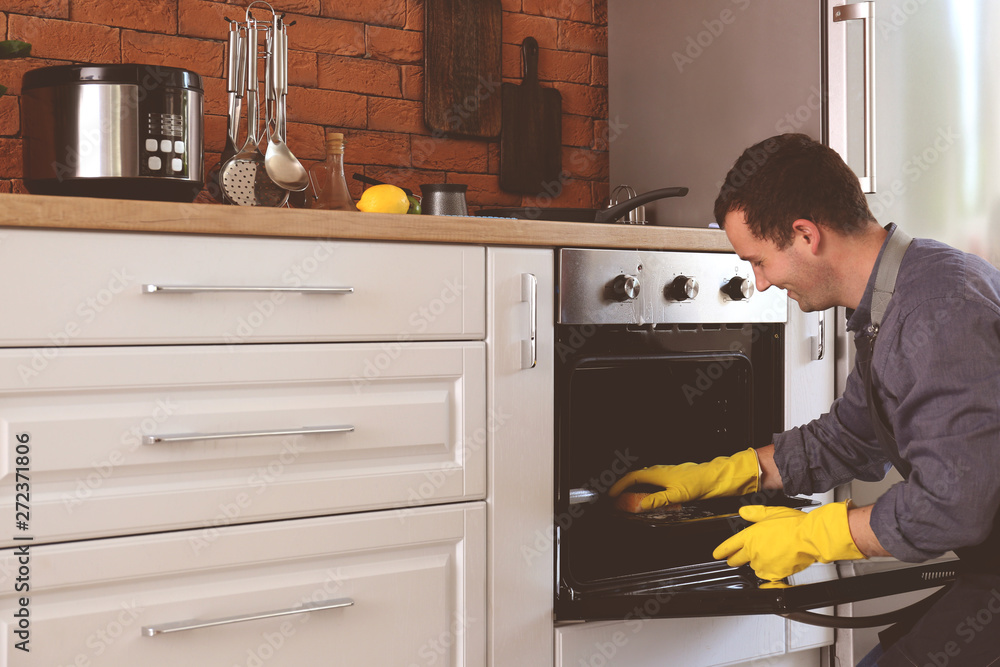 Man cleaning oven at home