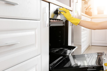 Woman cleaning oven at home