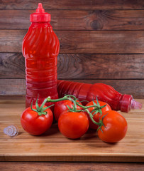 Tomato sauce in two plastic bottles and tomatoes branch