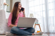 © weedezign - Happy asian woman talk on mobile and  typing laptop computer at home.female freelancer sitting on carpet on floor work at home in living room..