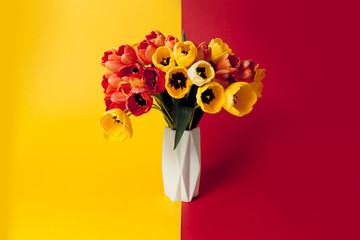 A bouquet of red and yellow flowers, tulip flowers in a white bowl. 