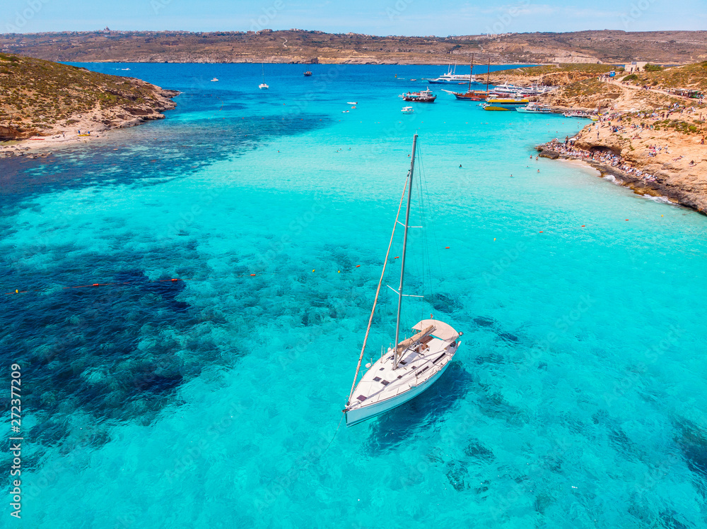 Concept paradise vacation. White yacht with sail in clear water of sea with sand. Blue Lagoon Comino Malta. Aerial view - obrazy, fototapety, plakaty 