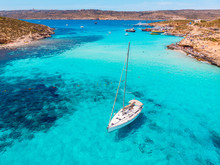 Concept Paradise Vacation. White Yacht With Sail In Clear Water Of Sea With Sand. Blue Lagoon Comino Malta. Aerial View