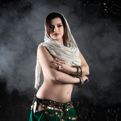 Sexy women performs belly dance in ethnic dress on dark smoky background, abstract art photography