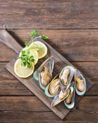 Raw kiwi mussels on a wooden Board on a wooden table. Rustic style