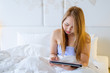 © Hide_Studio - Young woman using tablet on bed at home, with copy space,Business and technology concept background