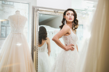 Wall Mural - Beautifu bride choosing wedding dress in a wedding salon