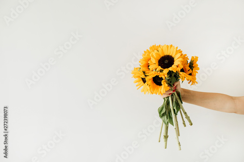 Women's hand hold yellow sunflowers bouquet on white background Fotobehang